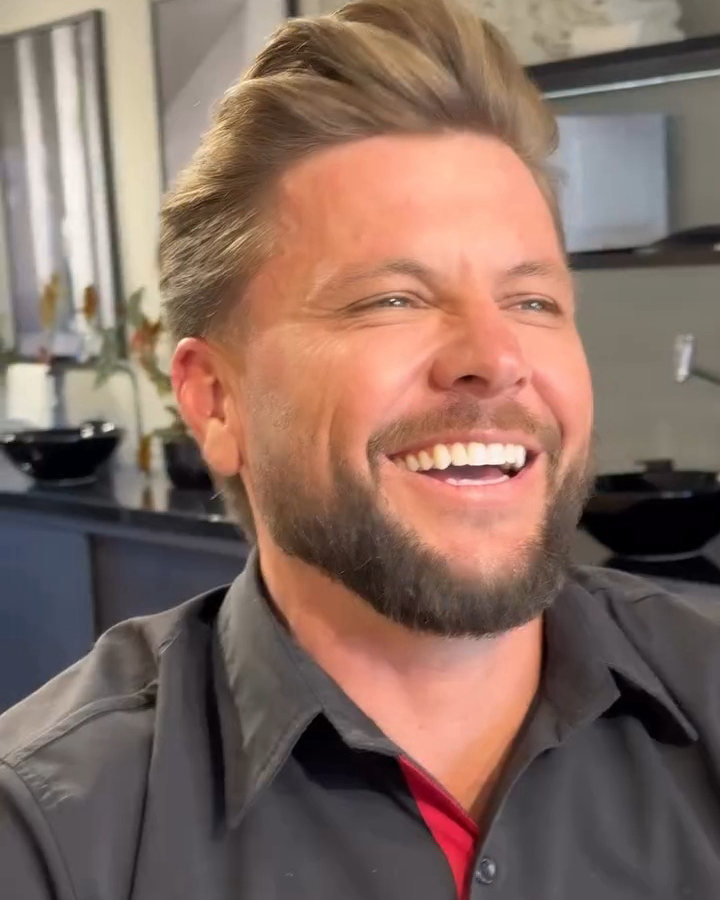 Cliente rindo com o cabelo penteado pra trás e a barba feita