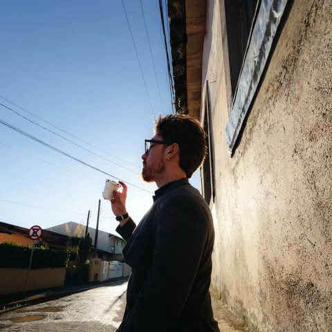 Homem tomando café na calçada de manhã