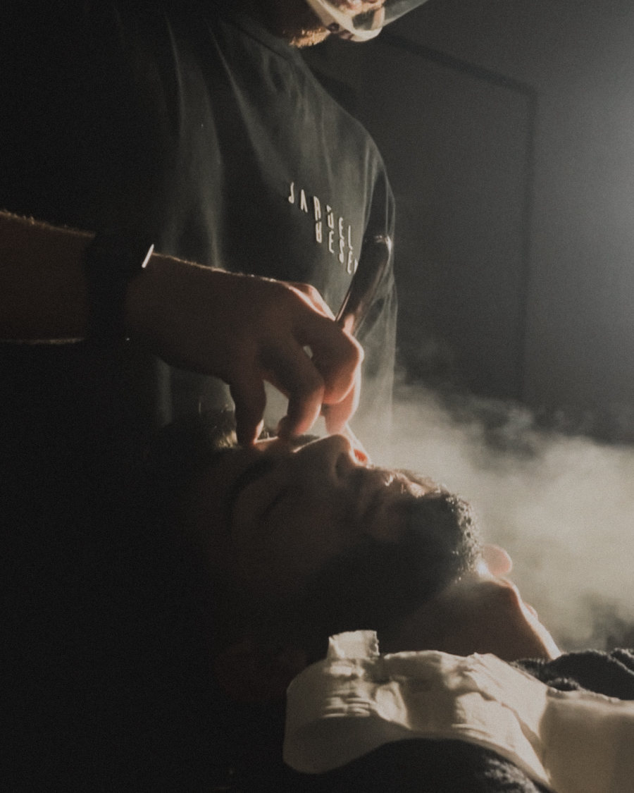 Barbeiro fazendo a barba com toalha quente e vapor